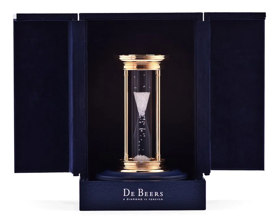DE BEERS HOURGLASS De Beers, Louis Glick & Company. Made in the early 2000s. Fine and elegant 24K yellow gold-plated desk hourglass with over 2000 rough diamonds as the grains. Accompanied by original fitted box, illuminating base, and booklet. To be sold without reserve