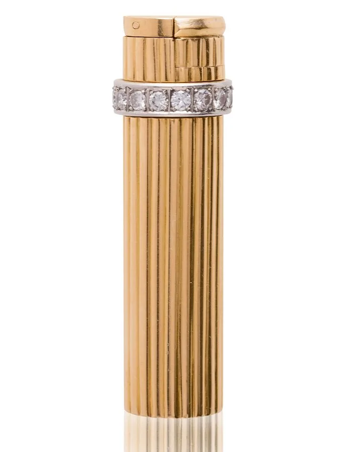 HERMES ELEGANT GOLD, PLATINUM AND DIAMOND LIGHTER, CIRCA 1950S Of round and cylindrical yellow-gold shape, highlighted by a rotating platinum diamond ring use to switch on the lighter. Signed Hermès. Gross weight: 65,4g. High: 6,7 cm. Diameter : 1,5 cm. Briquet de forme ronde et cylindrique en or, rehaussé par une bague amovible en platine sertie de diamants, utiliser pour allumer le briquet. Signé Hermès.