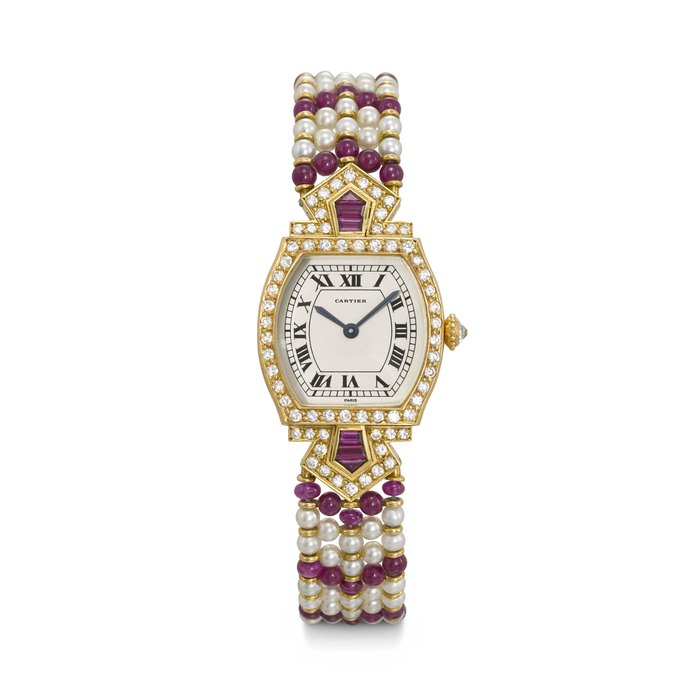 CARTIER. AN EXTREMELY RARE AND ELEGANT 18K GOLD, DIAMOND AND RUBY-SET TONNEAU-SHAPED WRISTWATCH WITH PEARL, RUBY BEAD AND DIAMOND-SET BRACELET TORTUE MODEL, CASE NO. A 100'136, CIRCA 1986