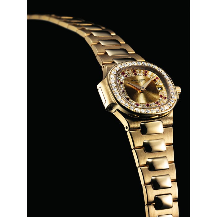 PATEK PHILIPPE. A LADY'S FINE AND RARE 18K GOLD, DIAMOND AND RUBY-SET CUSHION-SHAPED WRISTWATCH WITH DATE AND BRACELET SIGNED PATEK PHILIPPE, GENEVE, NAUTILUS MODEL, REF. 4700/103, MOVEMENT NO. 1'528'021, CASE NO. 2'823'844, MANUFACTURED IN 1985