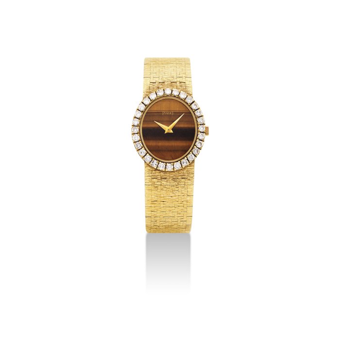 PIAGET. A LADY'S 18K GOLD AND DIAMOND-SET OVAL BRACELET WATCH WITH TIGER'S EYE DIAL SIGNED PIAGET, REF. 9814 A6, CASE NO. 220'184, MANUFACTURED IN 1973