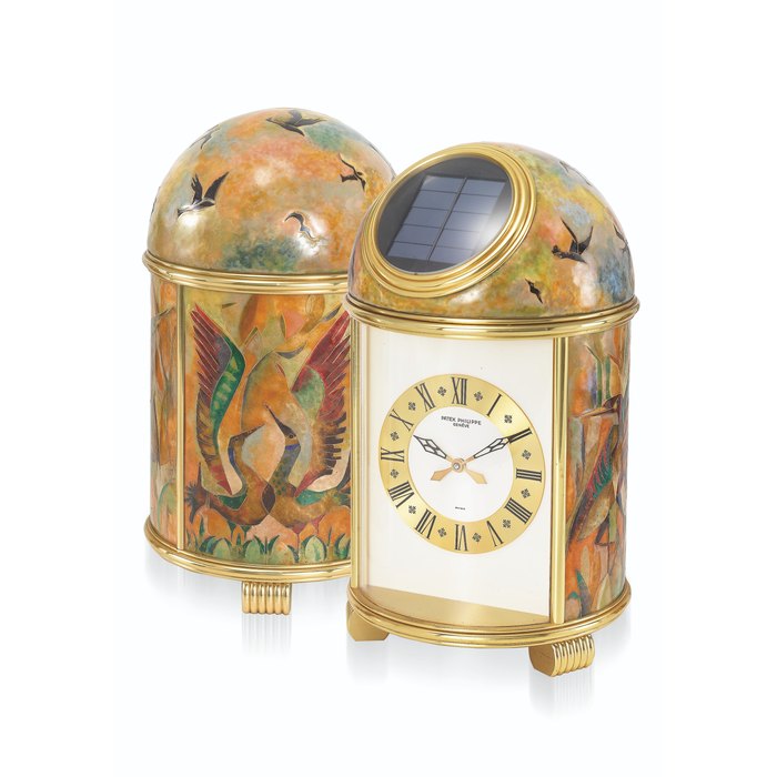 PATEK PHILIPPE. AN EXTREMELY ATTRACTIVE AND UNIQUE GILT BRASS SOLAR-POWERED TABLE CLOCK WITH CLOISONNE ENAMEL BY ELISABETH PERUSSET LAGGER, WITH BOX SIGNED PATEK PHILIPPE, GENEVE, DOME, “AVENTURIERS DES ROSEAUX”, REF. 1121, MOVEMENT NO. 1’803’464, MANUFACTURED IN 1976
